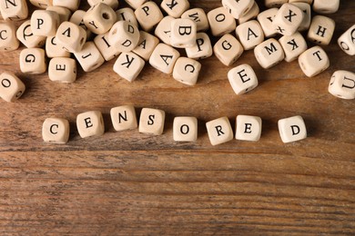 Photo of Small cubes with word Censored on wooden table, flat lay