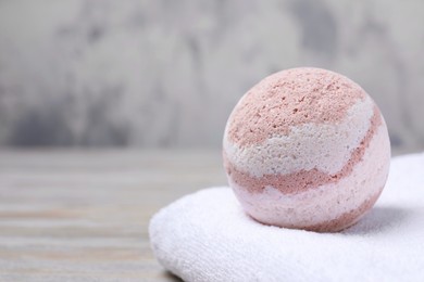 Photo of Bath bomb and towel on table, closeup. Space for text