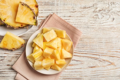 Plate with fresh pineapple slices on wooden background