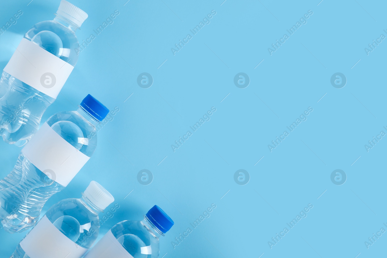 Photo of Bottles of water on color background, top view. Space for text