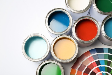 Paint cans and color palette on white background, top view