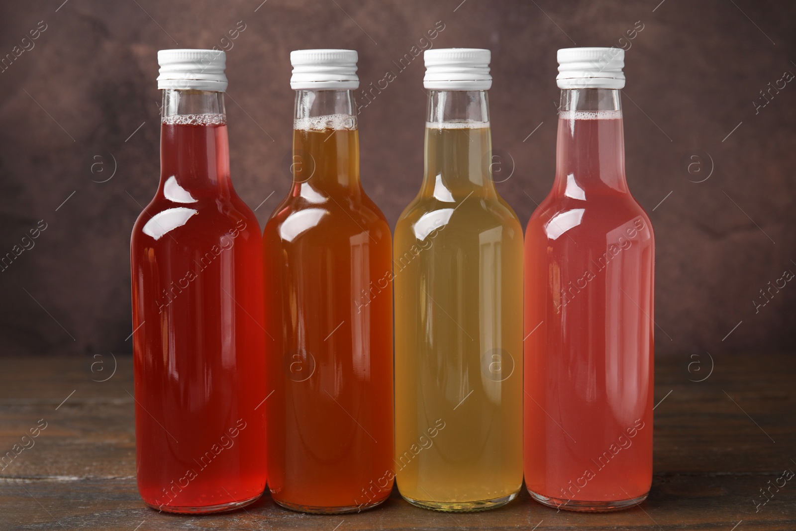 Photo of Delicious kombucha in glass bottles on wooden table