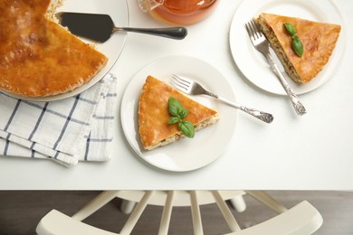 Photo of Delicious pie with meat and basil on white table, flat lay