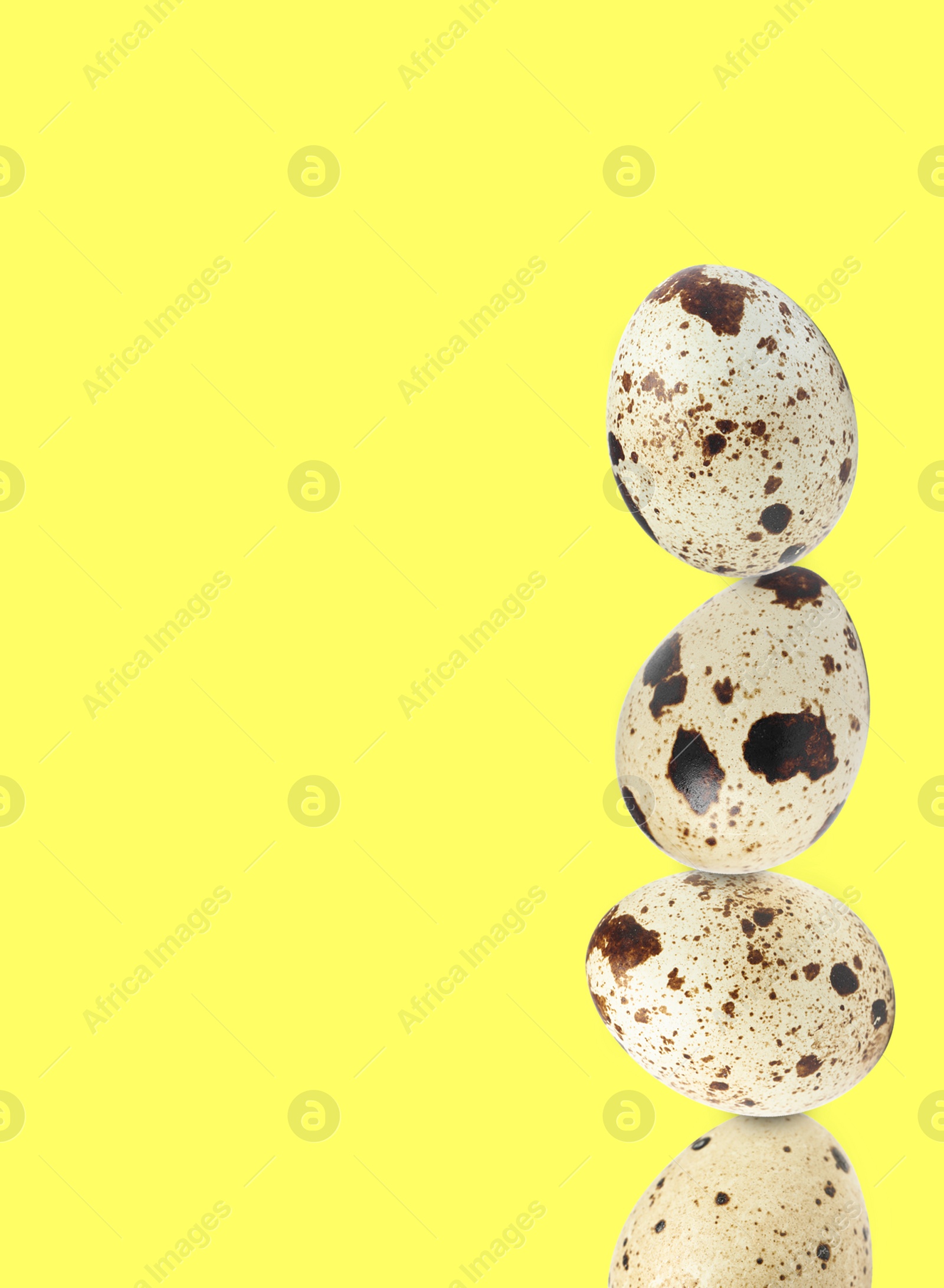 Image of Stacked speckled quail eggs on light yellow background. Space for text