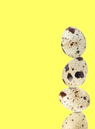 Stacked speckled quail eggs on light yellow background. Space for text