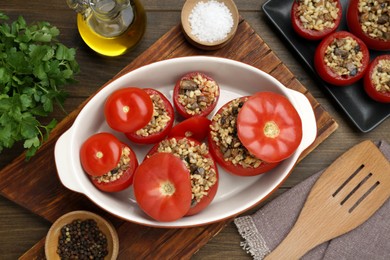 Photo of Delicious stuffed tomatoes with minced beef, bulgur and mushrooms on wooden table, flat lay