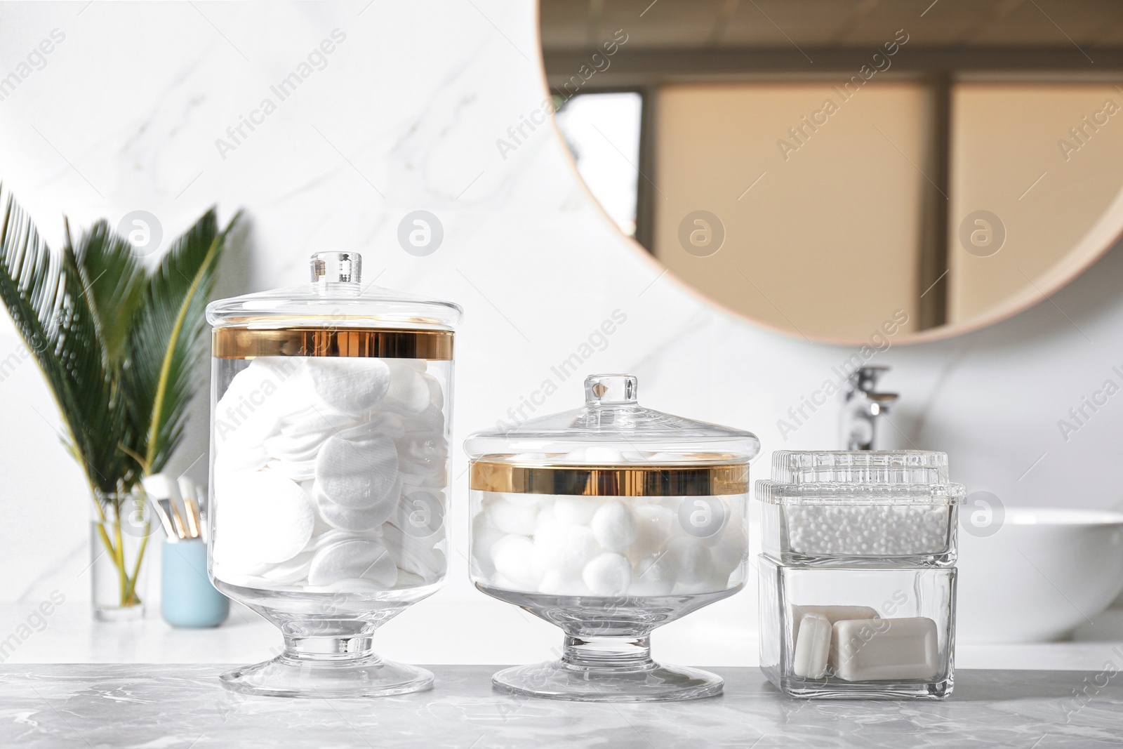 Photo of Cotton balls, swabs, pads and soap bars on light grey marble table in bathroom