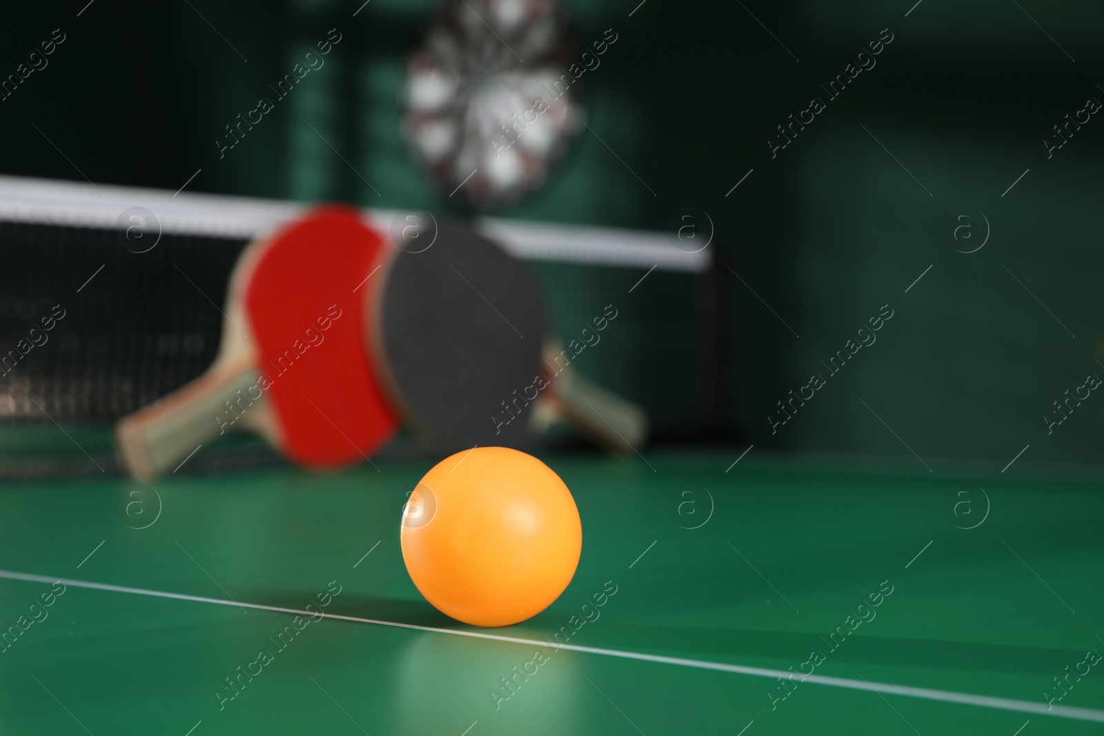 Photo of Orange ball on green ping pong table indoors. Space for text