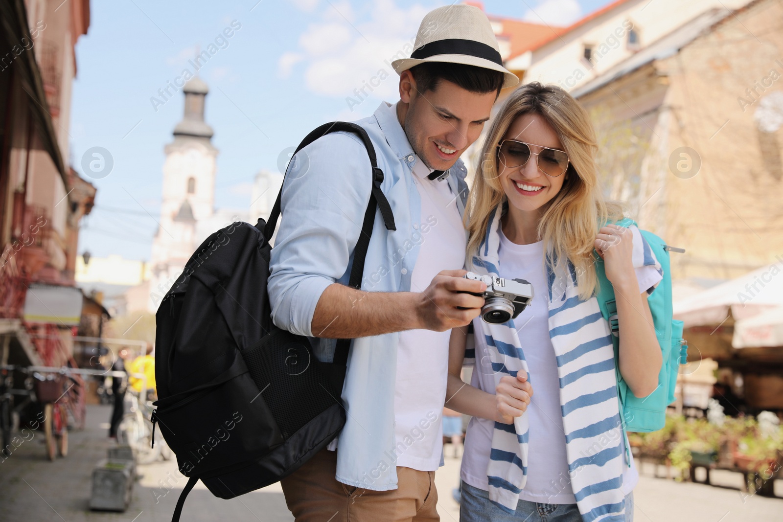 Photo of Happy couple of tourists with camera on city street