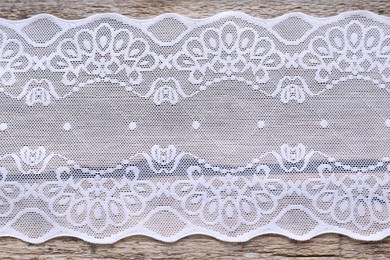 Photo of White lace on wooden table, top view