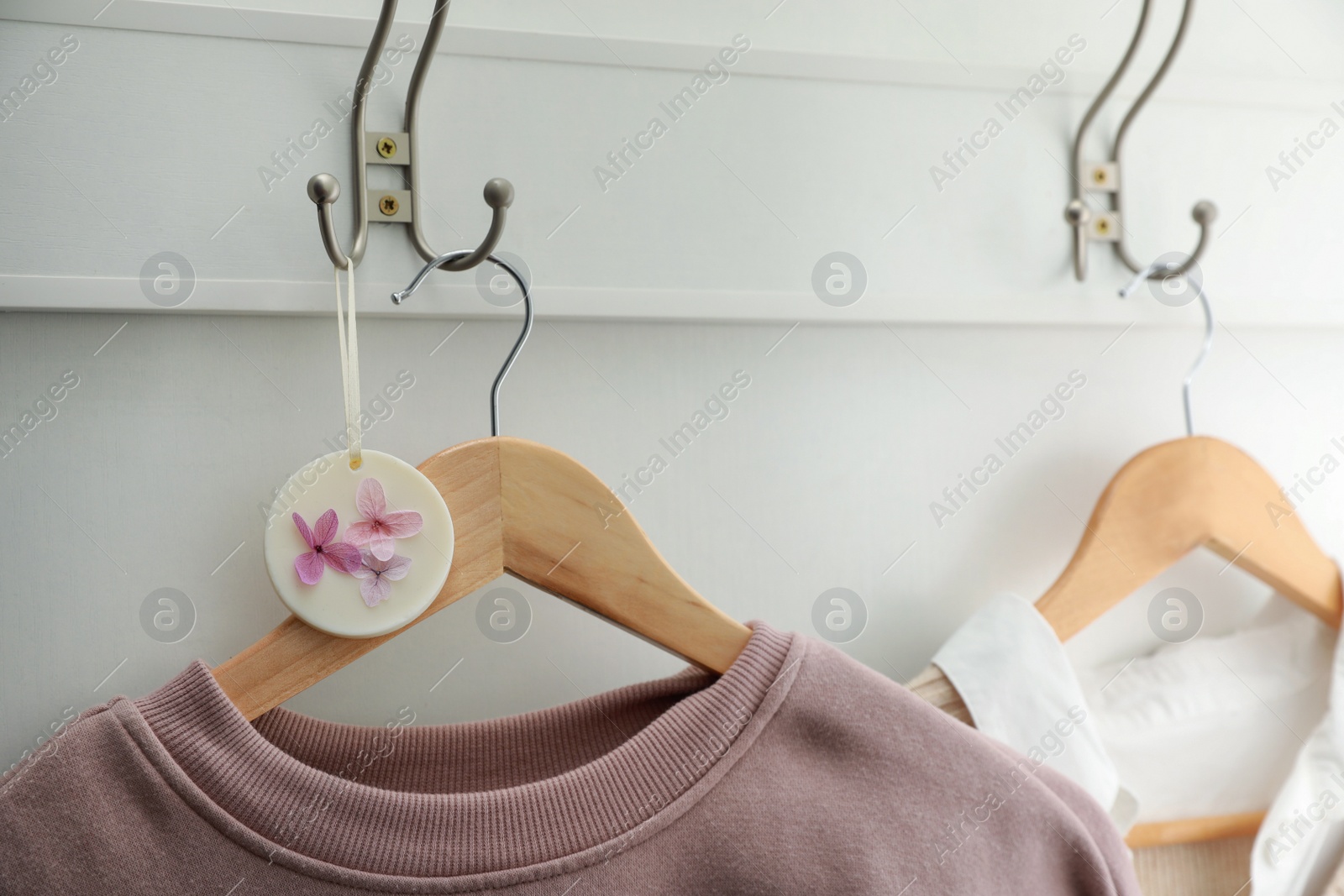 Photo of Beautiful scented sachet and stylish clothes on hooks