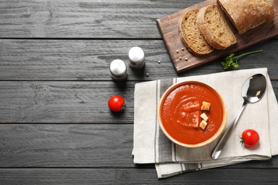 Photo of Fresh homemade tomato soup served with bread on wooden table, top view. Space for text