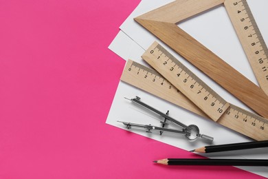 Different rulers, pencils and compass on pink background, flat lay. Space for text