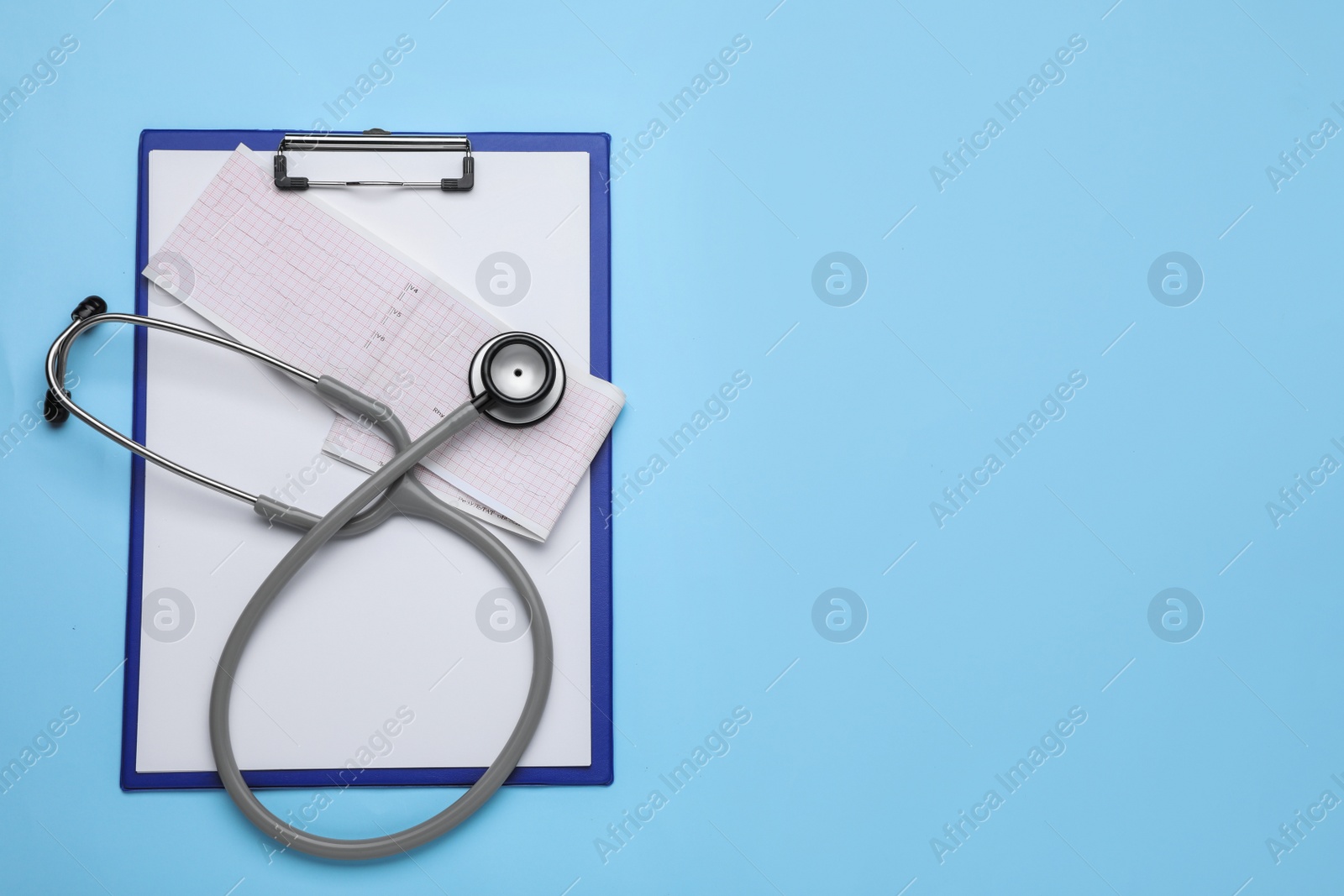 Photo of Stethoscope, clipboard and cardiogram paper on light blue background, top view. Space for text