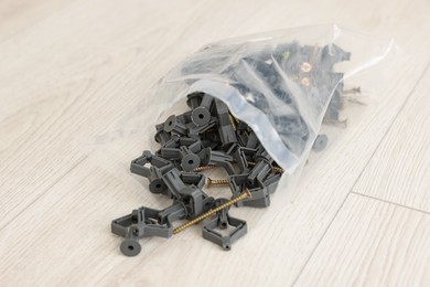 Photo of Bag with dowels and screws on wooden floor
