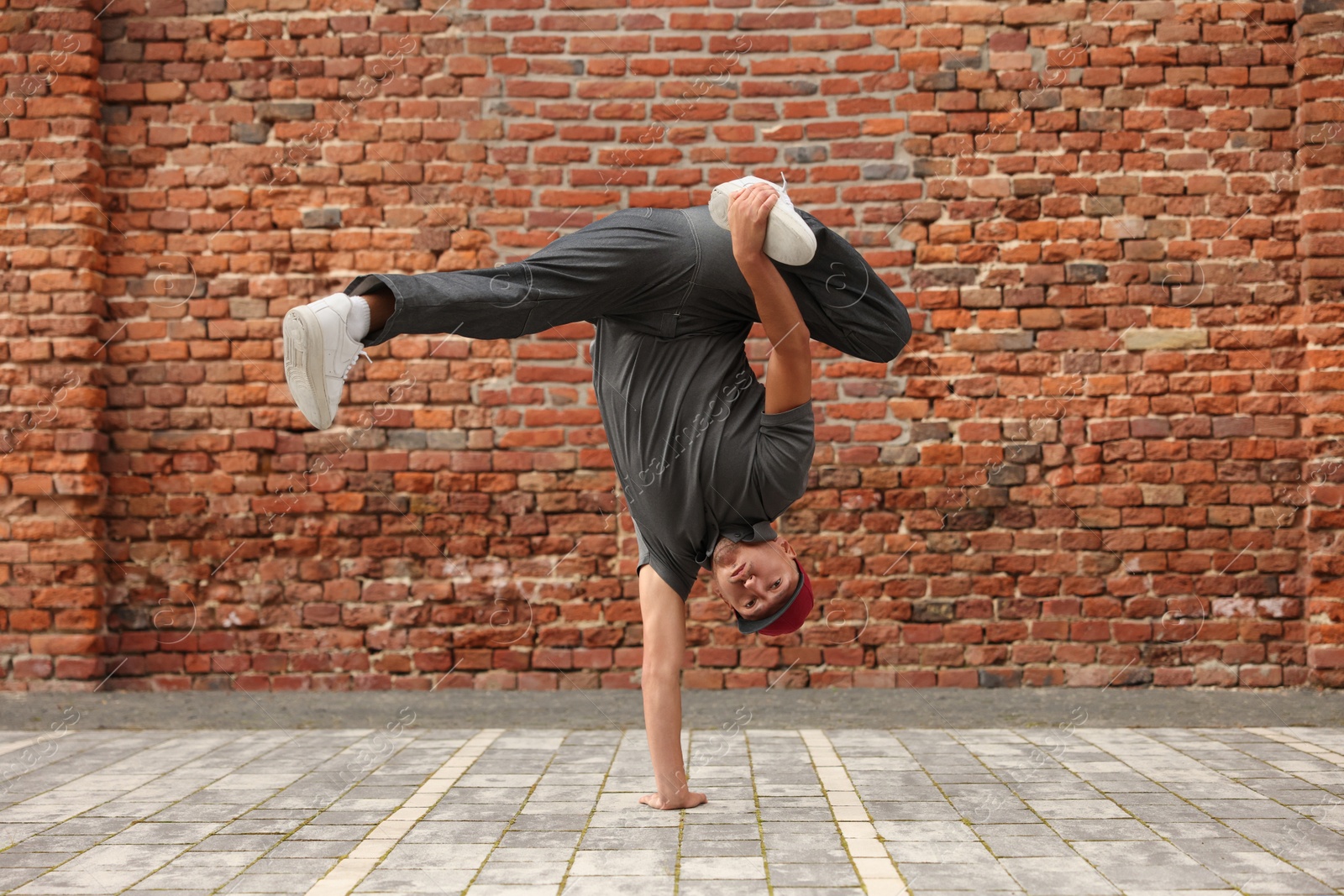 Photo of Man dancing hip hop near brick wall outdoors