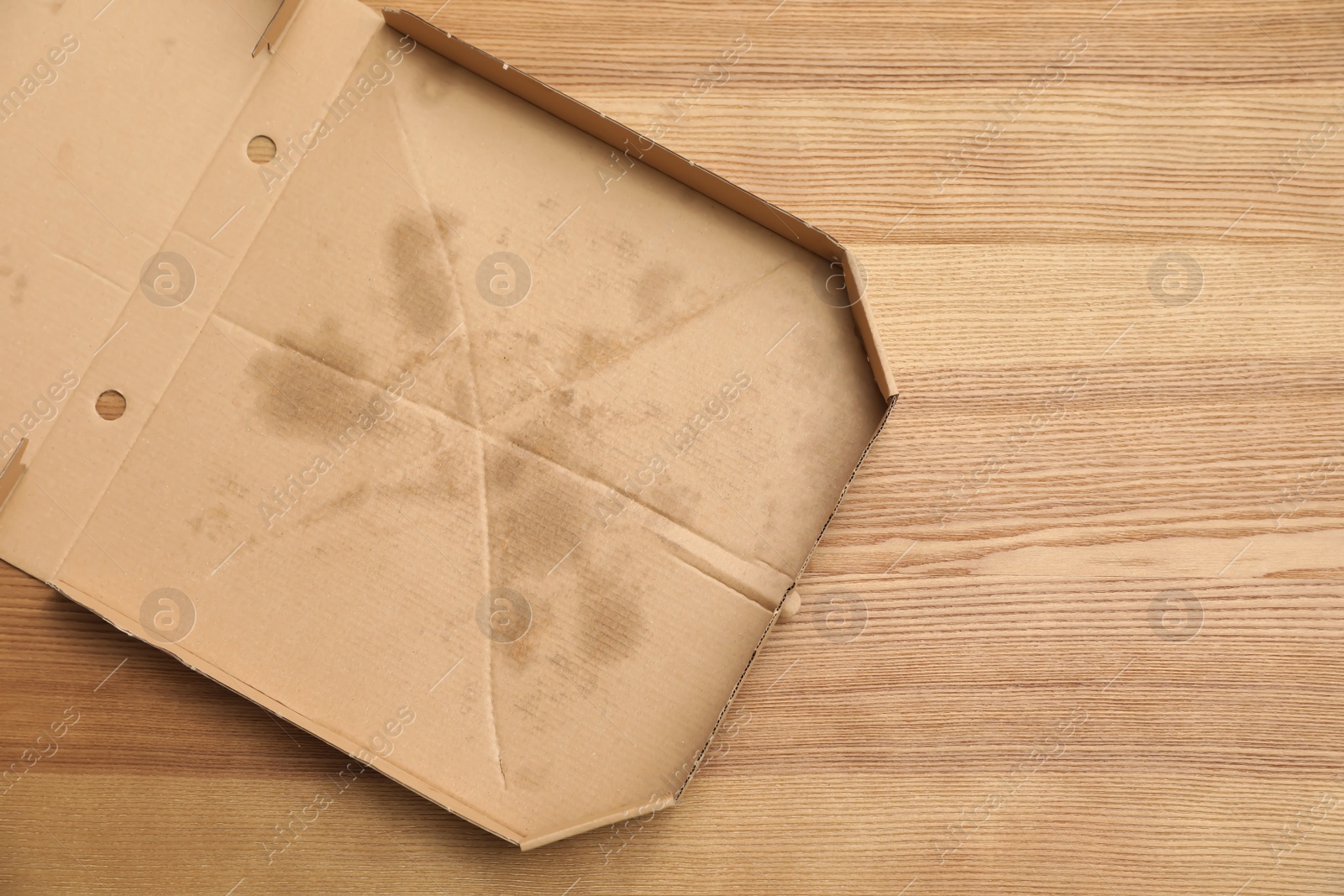 Photo of Cardboard pizza box on wooden background, top view with space for text