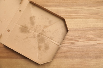 Cardboard pizza box on wooden background, top view with space for text