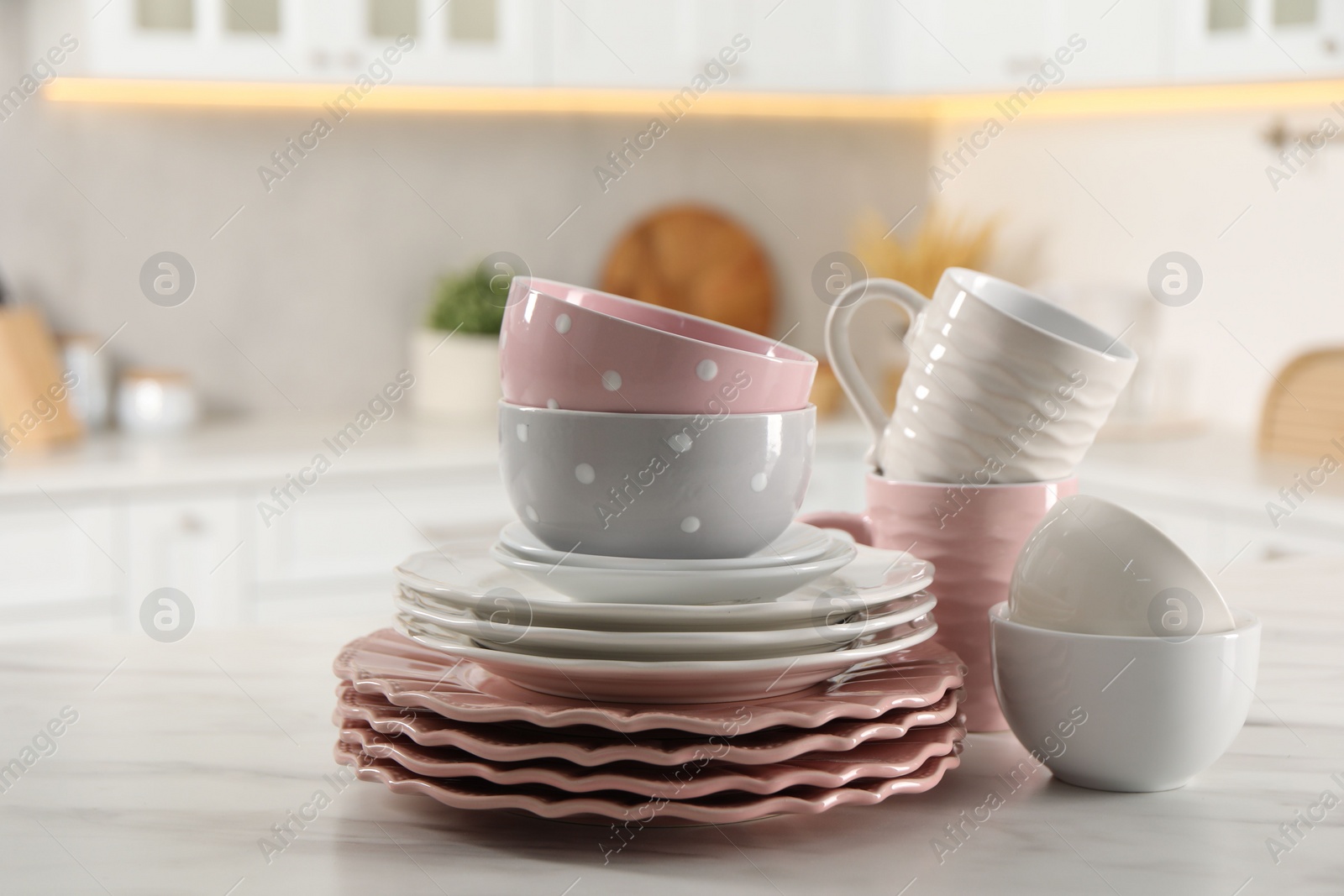 Photo of Many different clean dishware and cups on white marble table in kitchen