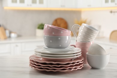 Many different clean dishware and cups on white marble table in kitchen