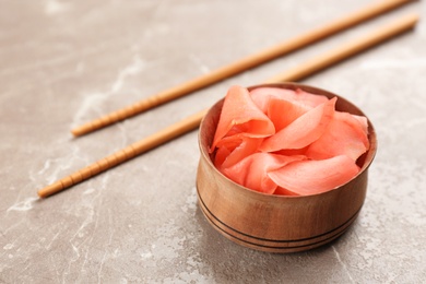 Photo of Spicy pickled ginger and chopsticks on grey table. Space for text