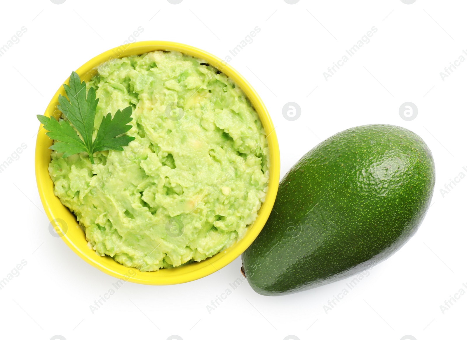 Photo of Bowl of tasty guacamole with basil and whole avocado on white background, top view