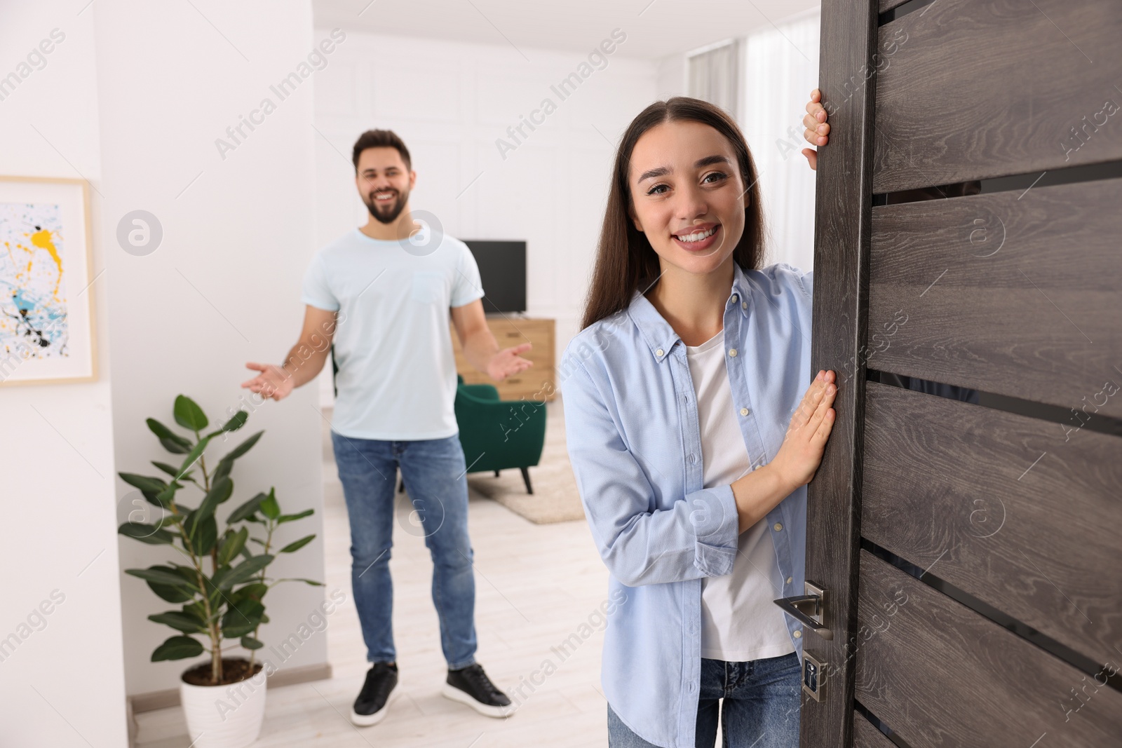 Photo of Happy couple welcoming at home. Invitation to come indoors