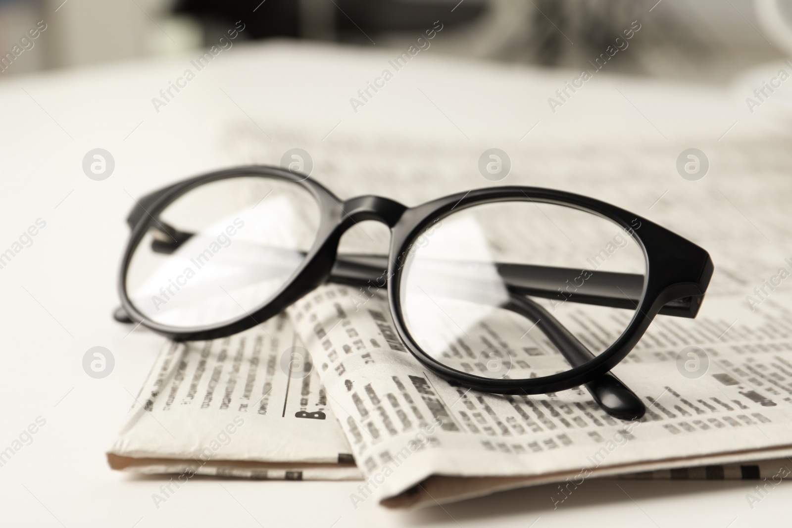 Photo of Newspapers and glasses on white table, closeup