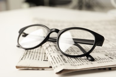 Photo of Newspapers and glasses on white table, closeup
