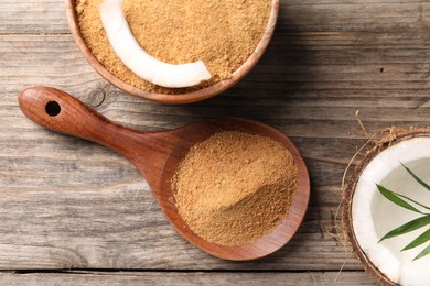 Photo of Coconut sugar in bowl, spoon and fruit on wooden table, flat lay