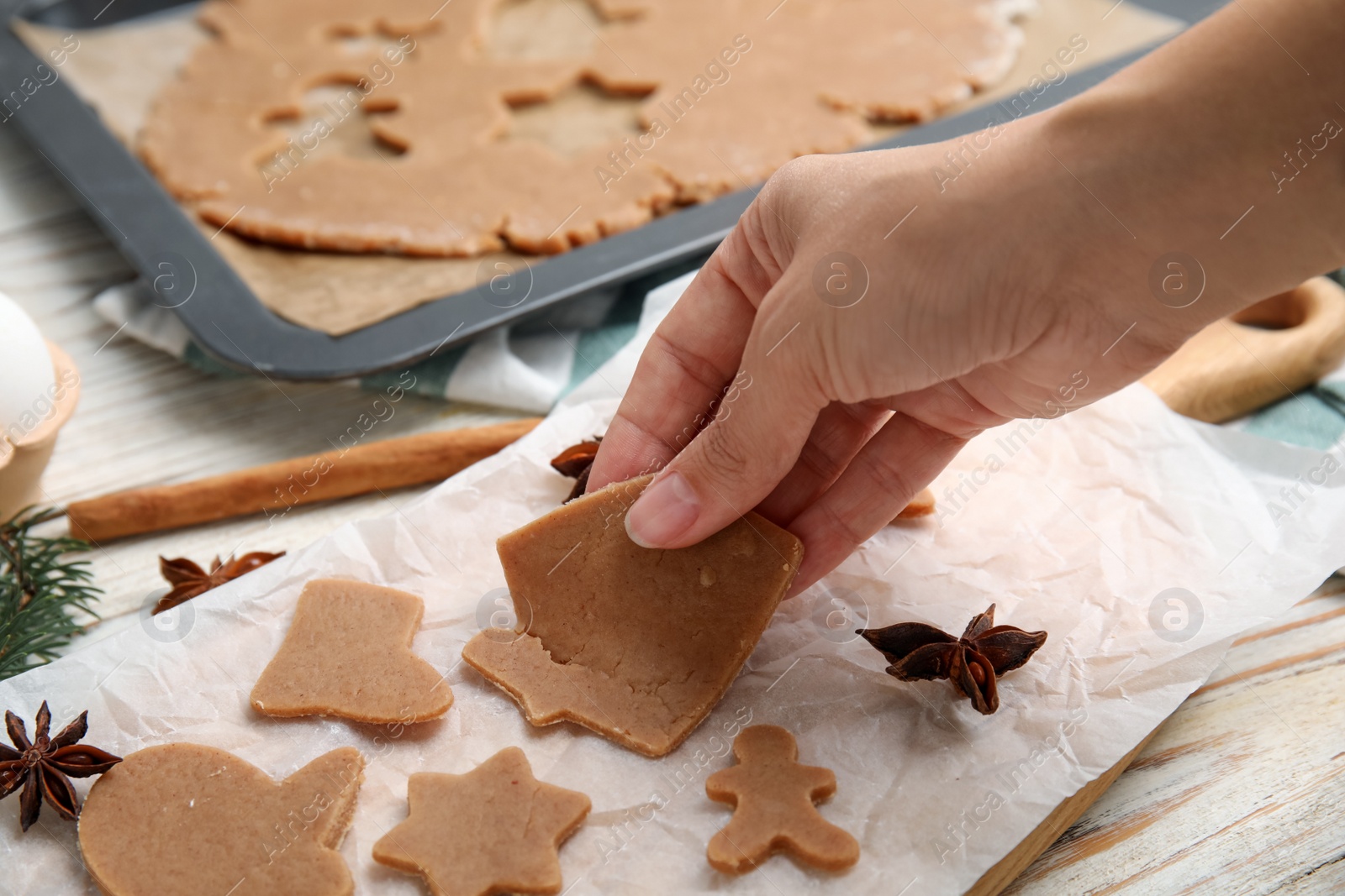 Photo of Woman making gingerbread Christmas cookies at white wooden table, closeup