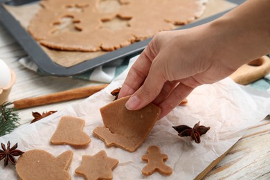 Woman making gingerbread Christmas cookies at white wooden table, closeup