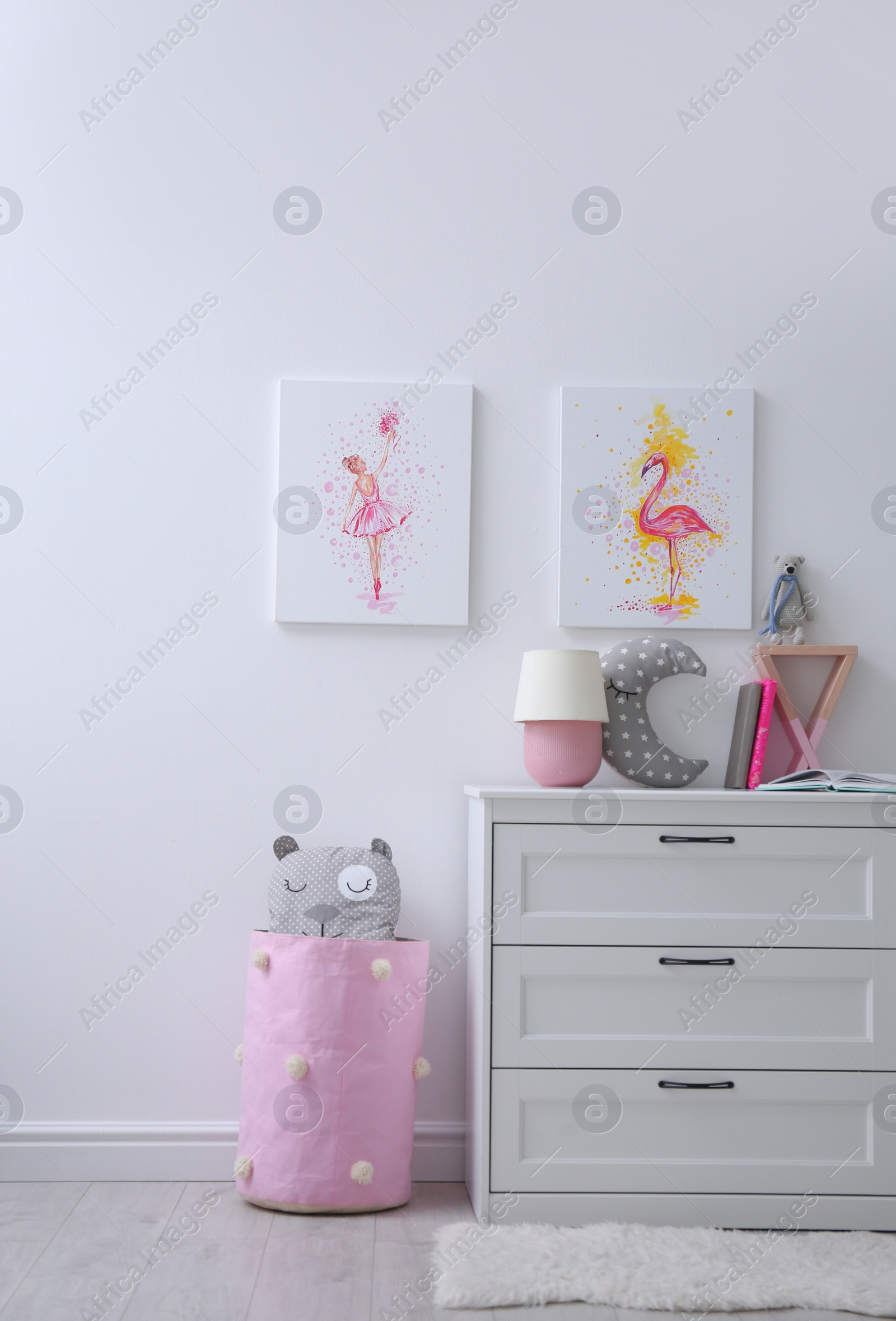 Photo of Chest of drawers and beautiful pictures in children's room. Interior design