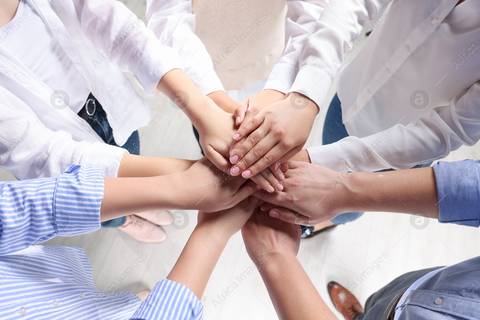 Photo of Group of people holding hands together indoors, above view. Unity concept