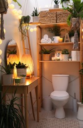 Photo of Stylish bathroom interior with toilet bowl and green plants