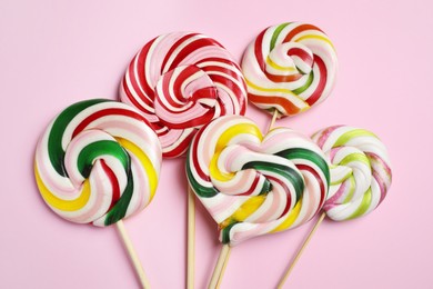 Photo of Sticks with different colorful lollipops on pink background, flat lay