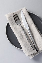 Stylish silver cutlery, plate and napkin on white background, top view