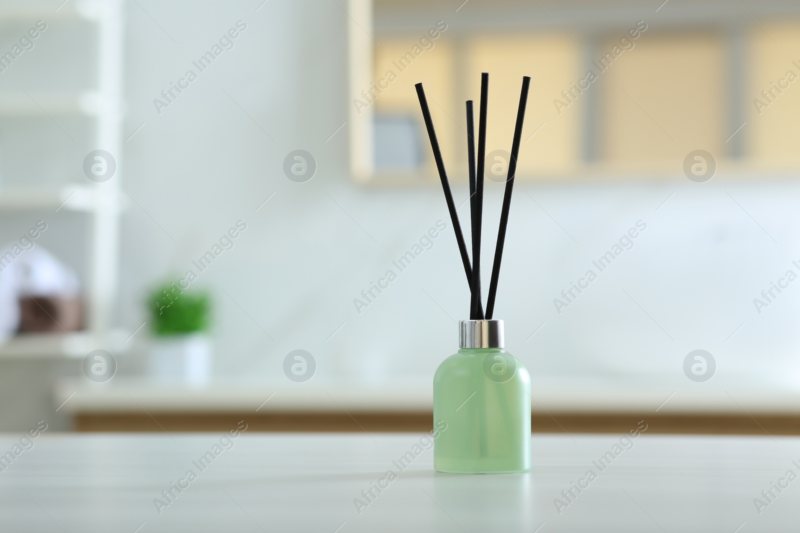 Photo of Aromatic reed air freshener on table indoors