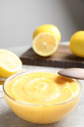 Photo of Delicious lemon curd in bowl on grey table. Space for text