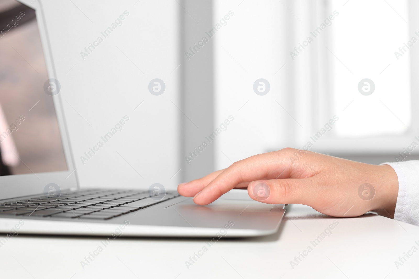 Photo of Woman working on laptop at white table in office, closeup