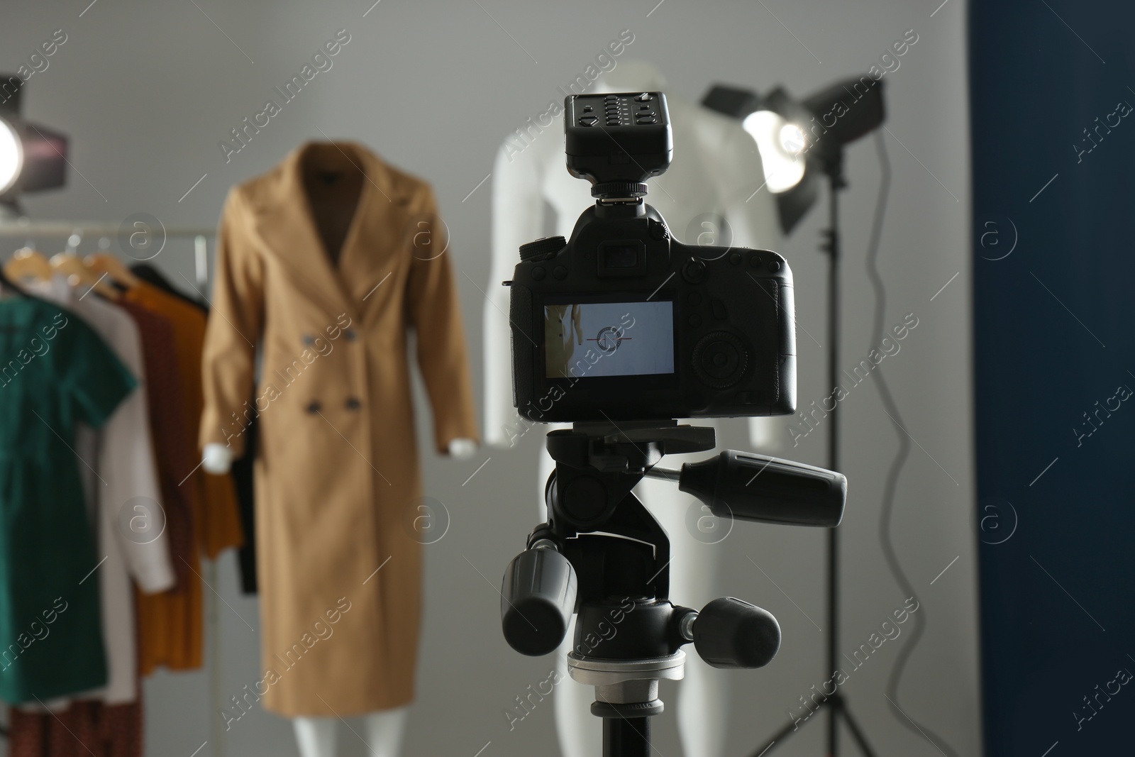 Photo of Ghost mannequins, clothes and professional lighting equipment in modern photo studio, focus on camera