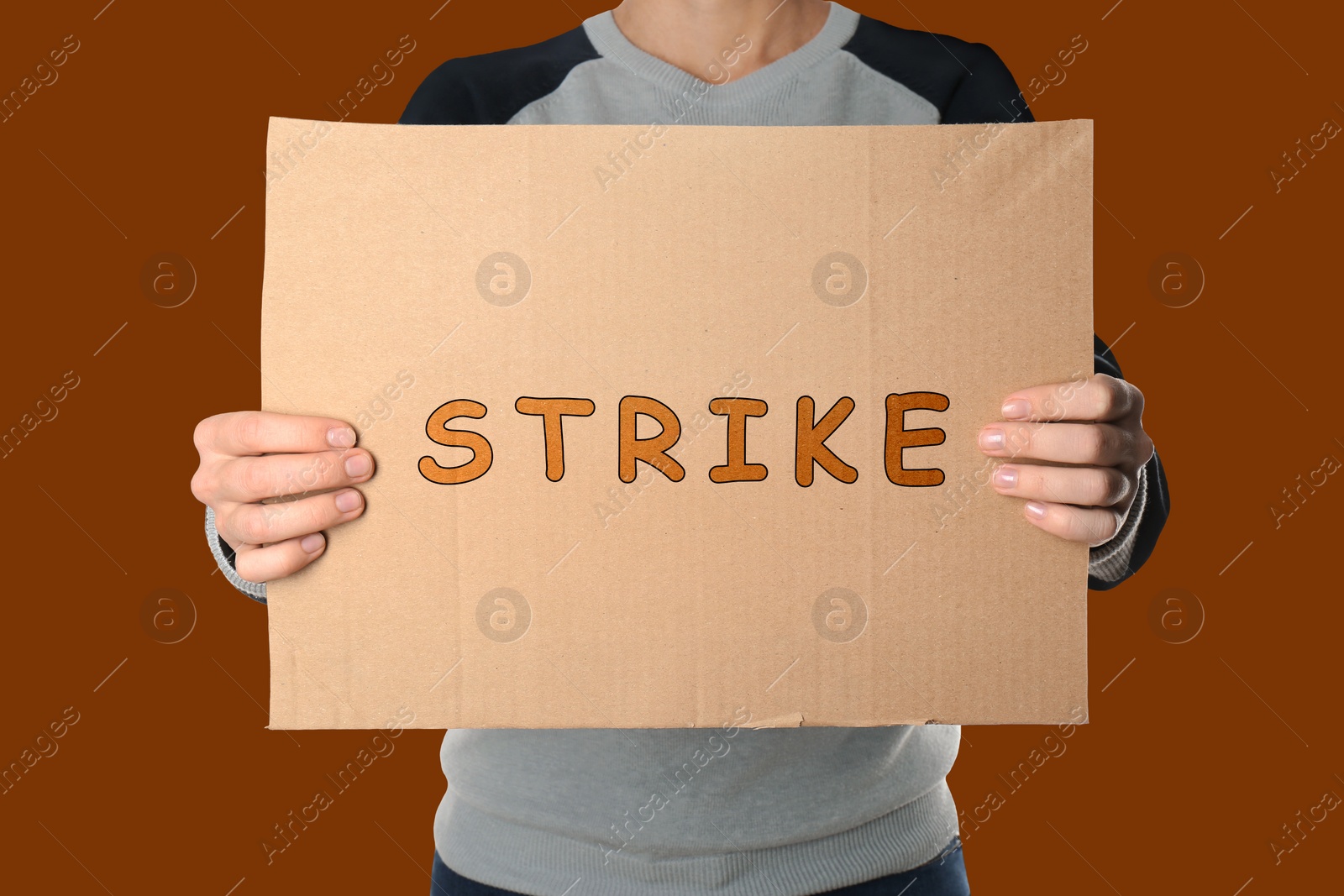 Image of Woman holding Strike sign on dark orange background, closeup