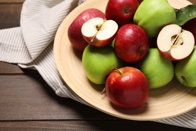 Photo of Plate with fresh ripe apples and leaf on wooden table, closeup