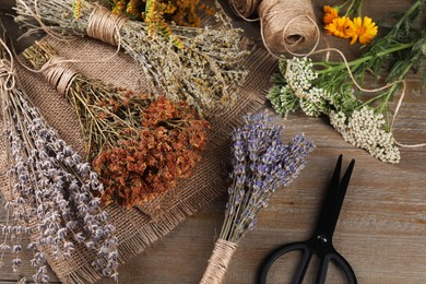 Different herbs, thread and scissors on wooden table, above view