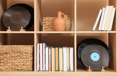 Photo of Wooden shelving unit with vinyl records near beige wall indoors