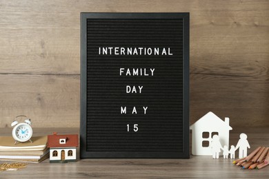 Photo of Letter board with text International Family Day May 15, decorative houses and stationery on wooden table