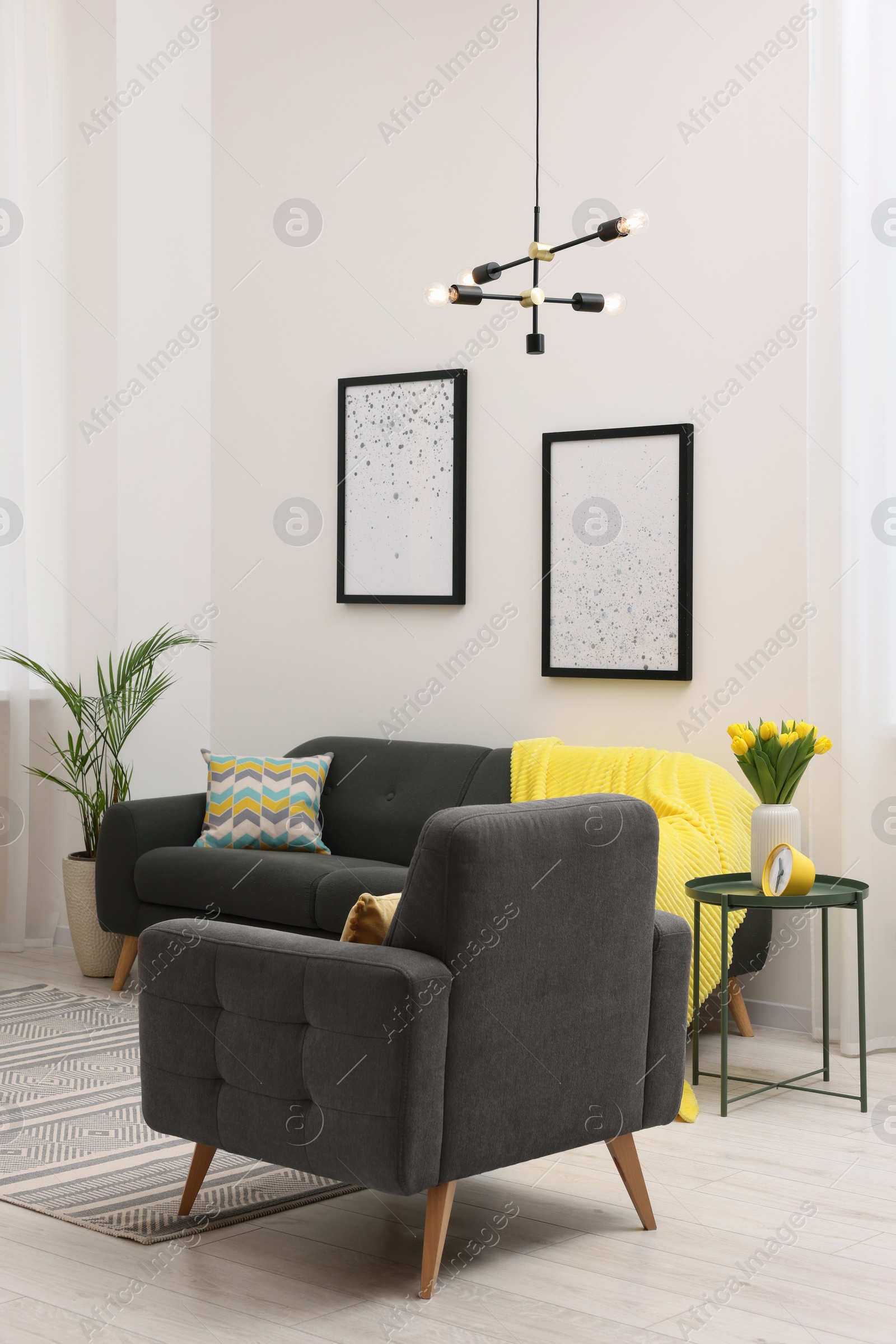 Photo of Spring atmosphere. Stylish living room interior with comfortable furniture and bouquet of beautiful yellow tulips