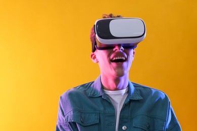 Photo of Young man with virtual reality headset on yellow background. Space for text