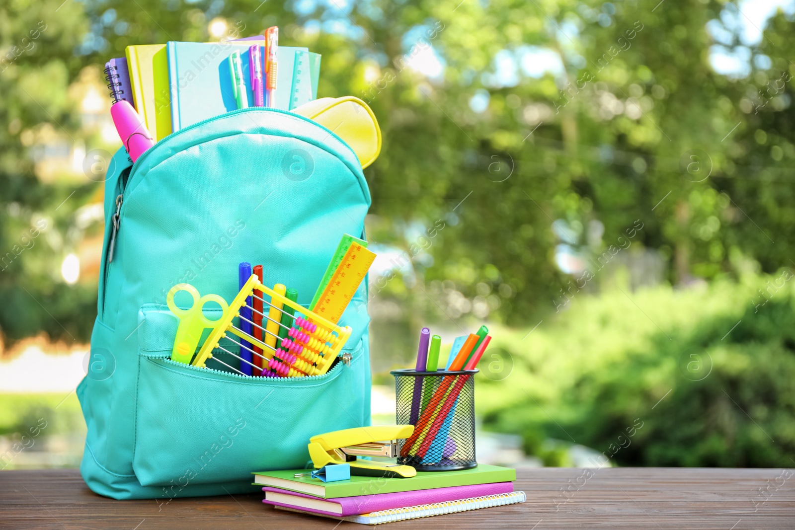 Photo of Bright backpack and school stationery on table outdoors, space for text