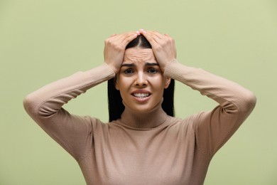 Photo of Woman suffering from migraine on light green background